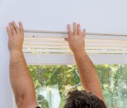 A male installing venetian blinds
